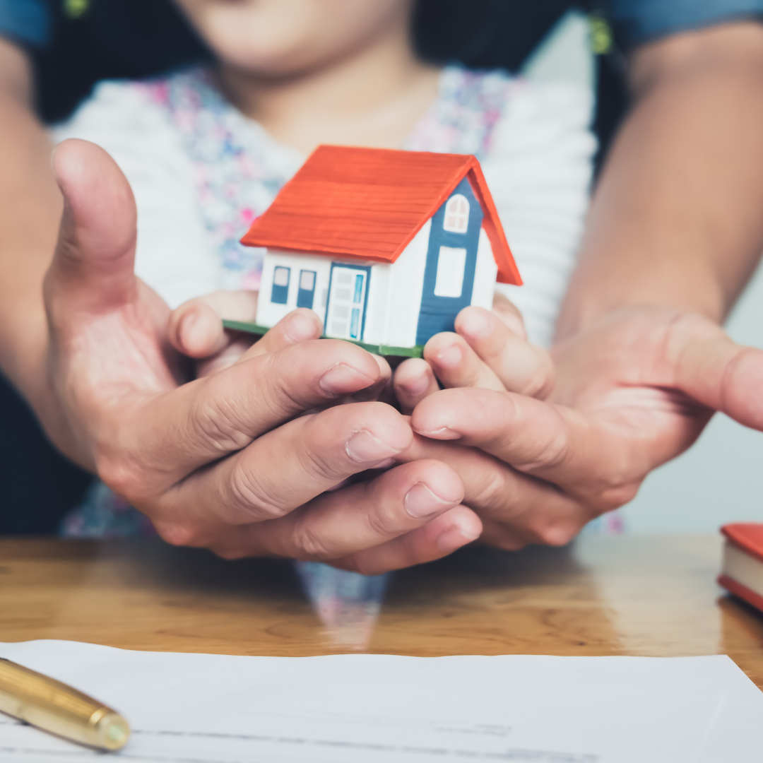 asset protection hands holding white house orange roof blue door